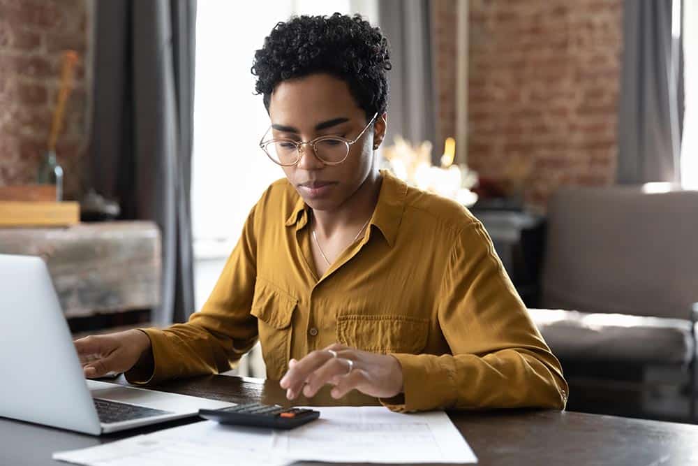 Woman Doing Finances on a Calculator and Laptop Computer