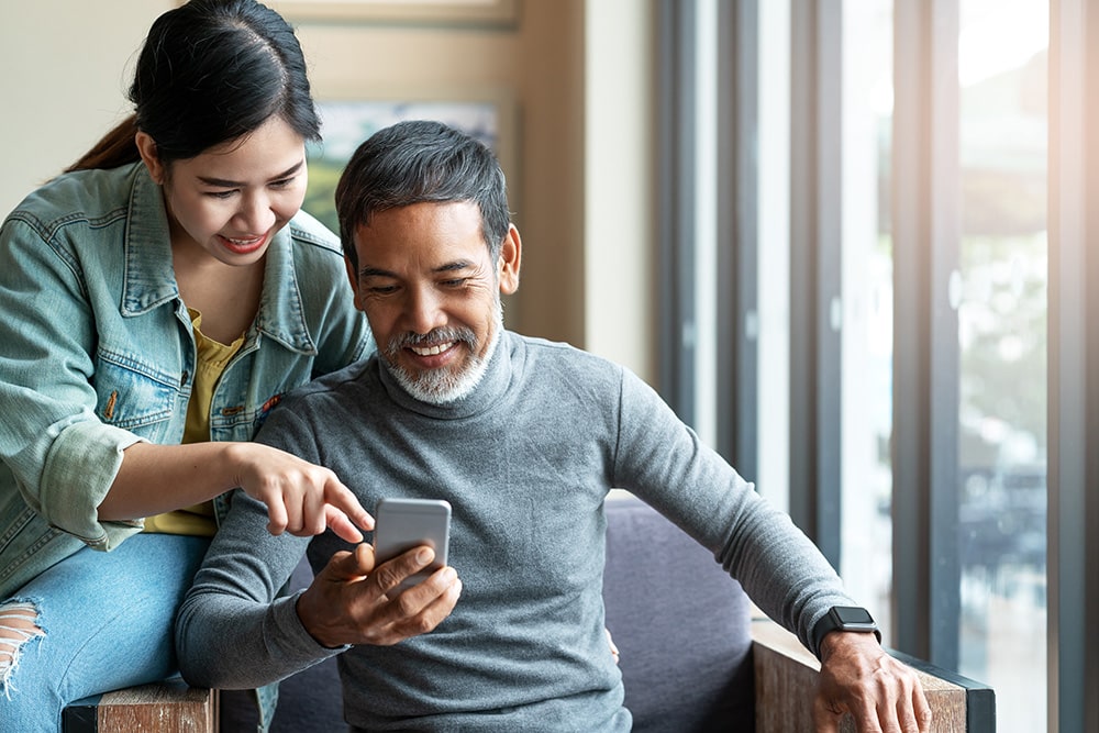 Man and wife sitting looking at their mobile phone